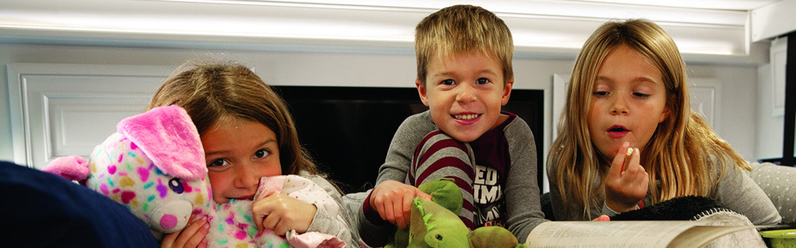 Underrated theme park destinations - 3 siblings and stuffed animals together on bed